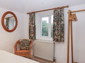 A bedroom with a mirror and a chair at Orchard Cottage in Dawlish