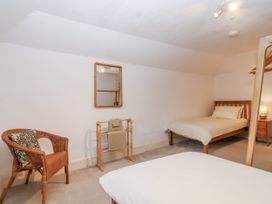 A bedroom with a bed and a chair at Orchard Cottage in Dawlish