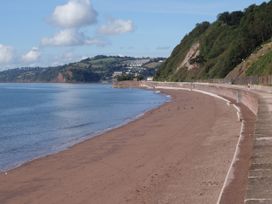 A beach with a pathway and hills in the background at Orchard Cottage in Holcombe
