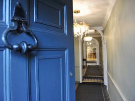 A view of a hallway with chandelier and door at ASH HOUSE in Wincanton