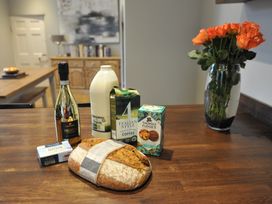 A kitchen table with prosecco, milk, coffee, biscuits, and bread at ASH HOUSE in Wincanton