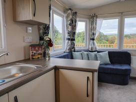 A living room with a couch and a kitchen sink in caravan NEW Uplyme