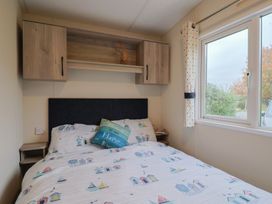 A bedroom with a bed and shelves at caravan NEW Uplyme