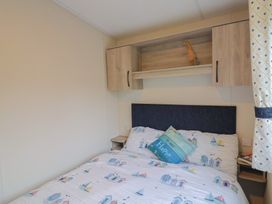 A bedroom with a bed and shelf at caravan NEW Uplyme