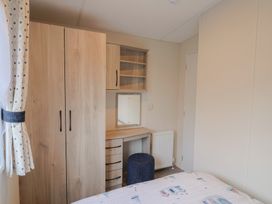A bedroom with a wardrobe, desk, mirror, and chair at caravan NEW in Uplyme
