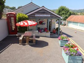 An outdoor reception area with a shop and a table with an umbrella at caravan NEW in Uplyme
