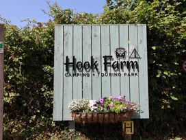 A sign for Hook Farm Camping and Touring Park with flowers at Uplyme