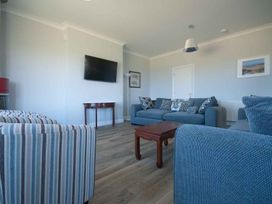 A living room with a sofa and television at Chynoweth in Crantock