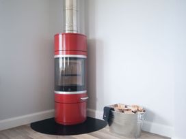 A stove and firewood bucket in a living room at Chynoweth in Crantock