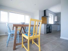 A kitchen with a dining table and colorful chairs at Chynoweth in Crantock