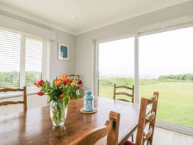 A dining room with a table and flowers at Chynoweth in Crantock
