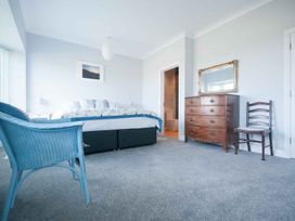 A bedroom with a bed, nightstand and a chair at Chynoweth in Crantock