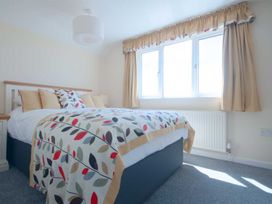 A bedroom with a bed and windows at Chynoweth in Crantock