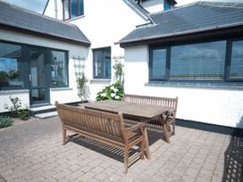 A patio area with a wooden table and benches at Chynoweth in Crantock