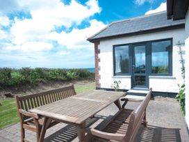 An outdoor dining area with wooden table and benches at Chynoweth Crantock