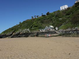 A beach with a house on a hill at Chynoweth in Crantock