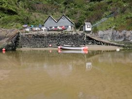 A boat at a rocky shoreline with a house in the background at Chynoweth in Crantock