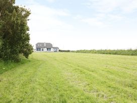 A house in a field with grass and trees at Chynoweth in Crantock