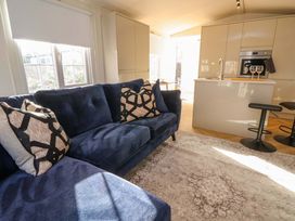 A living room with a blue sofa and kitchen island at Lodge in Talacre