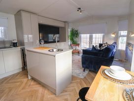 A kitchen and living room with a sofa and dining area at Lodge in Talacre