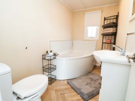 A bathroom with a bathtub, sink, and toilet at Lodge Talacre