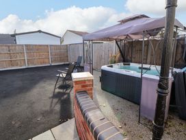 An outdoor area with a hot tub and chairs at Lodge in Talacre