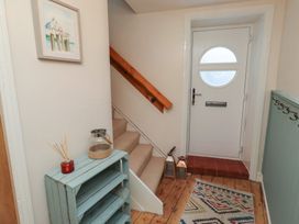 A hallway with a staircase and door at Corner Cottage in Seahouses