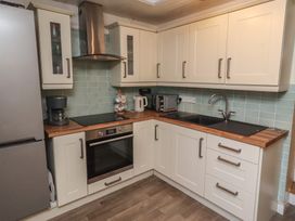 A kitchen featuring a refrigerator, oven, sink, coffee maker, and cabinets at Corner Cottage in Seahouses