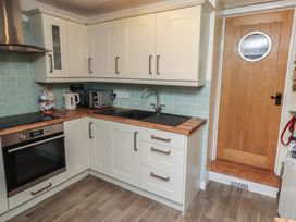 A kitchen with cabinets and appliances at Corner Cottage in Seahouses