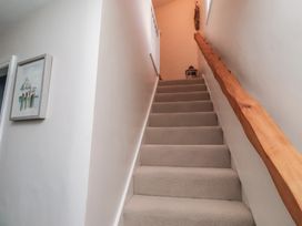 A stairway with a handrail and framed artwork at Corner Cottage in Seahouses