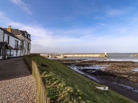 An outdoor area with buildings and a view of the water at Corner Cottage in Seahouses
