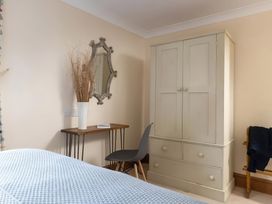 A bedroom with a wardrobe, table, chair, and mirror at The Granary, Engollan near St Merryn