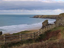 A view of a beach and ocean with a fence at The Granary, Engollan near St Merryn