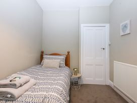 A bedroom with a single bed and a door at 3 Bay View Terrace in Llandegfan