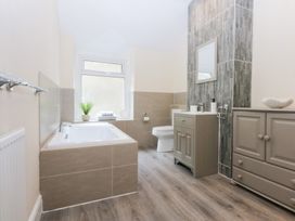 A bathroom with a bathtub, toilet, sink, and cabinet at 3 Bay View Terrace in Llandegfan