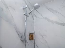 A shower area with a showerhead and soap dispenser at Derwent in Ulverston