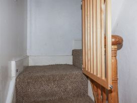A staircase with a wooden railing and carpet at Blowing House Cottage in Perranporth