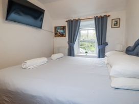 A bedroom with a bed and television at Blowing House Cottage in Perranporth