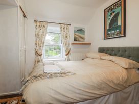 A bedroom with a bed and window at Blowing House Cottage in Perranporth