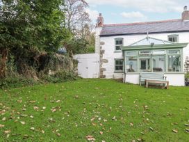 A garden with a house and conservatory at Blowing House Cottage in Perranporth