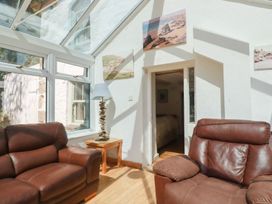 A conservatory with two brown sofas and a lamp at Blowing House Cottage near Perranporth