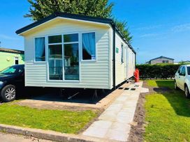 A mobile home with a car parked beside it at a holiday park