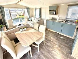 A living room with sofa and dining area at a holiday home in an outdoor setting