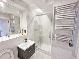 A bathroom with a shower, sink, towel rail, and toilet