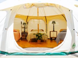 A bedroom setup inside a tent with beds and lamps at 