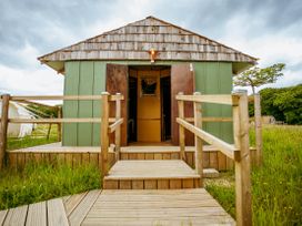 A cabin entrance with wooden steps and railing in a grassy area