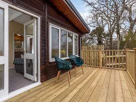 A deck with green chairs and wooden railing at Kilninver Chalet