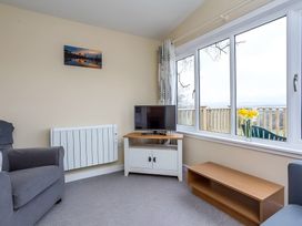 A living room with a TV and armchair at Kilninver Chalet