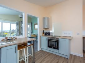 A kitchen with appliances and bar stools at Kilninver Chalet