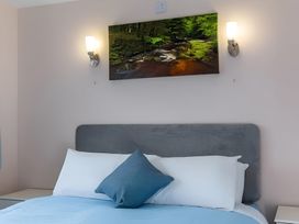 A bedroom with a bed and wall art featuring a stream at Kilninver Chalet